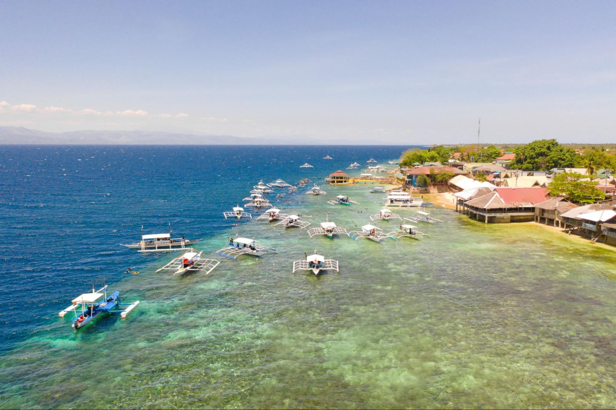 Boats near the shore in sunny weather. Seascape with coral reef near the shore